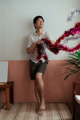 Happy asian gay enjoy playing the tinsel in his hands.