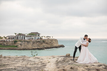 Fototapeta na wymiar Latino bride and groom kissing near a cliff