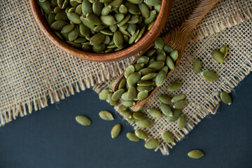 pumpkin seeds in a wooden bowl and vintage scoop. Close up on a black background. copy space for text