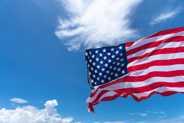 Waving USA flag under blue sky background.