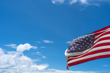 Waving USA flag under blue sky background.