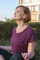 Senior sporty woman meditating in the Lotus position on the front lawn.Concept of active lifestyle and healthcare in mature age.