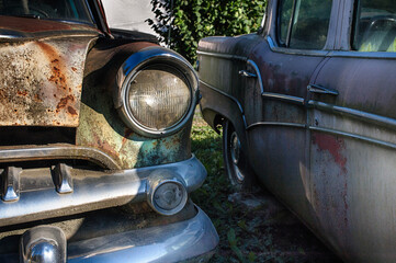 Two vintage cars rusting away.
