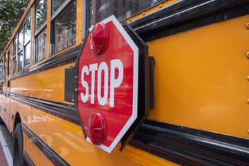 orange and black school bus side with swing out stop sign