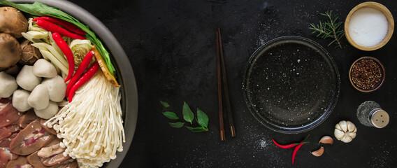 Japanese Sukiyaki in traditional Cast Iron Pot. Chabu sukiyaki and Empty plate on a dark metal background. Top view with copy space.