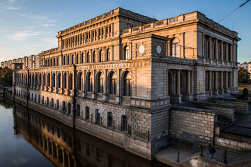 Naklejka premium Kaliningrad art Museum building on sunrise reflected in the river still water. Blue sky, high contrast.