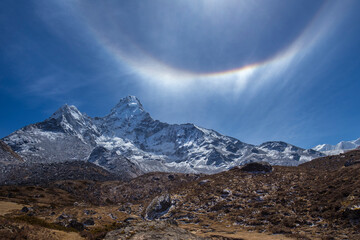 Snow-capped Mt Ama Dablam in the Himalayas with sun halo above in the bright blue sky.