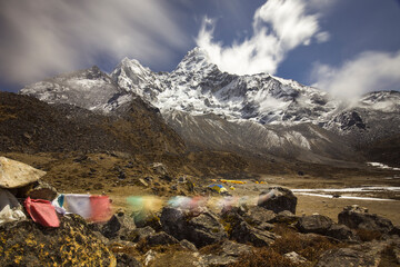 Long exposure shot of snow-capped Mt Ama Dablam in the Himalayas. Blurred Buddhist prayer flags in...
