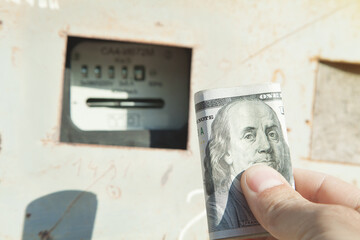 Male hand holding dollar banknote. Kilowatt hour electric meter. Power