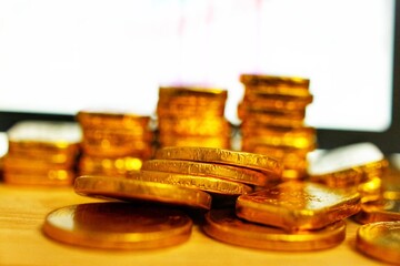 Gold coins placed in the concept of saving, gold investment education Forex trading, stock table background blur
