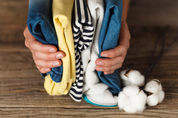 Hands hold a stack of organic clothing and cotton colors. Eco friendly fabric shop.