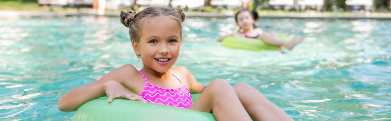 horizontal image of girl looking at camera while floating in pool on swim ring