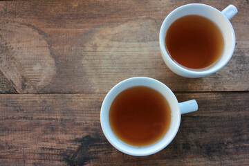 Two white ceramic cups of tea on wooden table from above. Selective focus. Top view, copy space