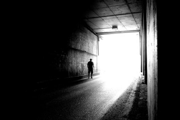 Moving silhouette of a young man in a dark tunnel in blur.