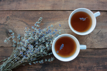 Cups of herbal tea with lavender flowers on wooden table from above. 