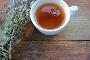 Cup of herbal tea with lavender flowers on wooden table from above. 