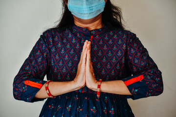Portrait of Indian female wearing medical mask doing  namaste with hands. Concept of greeting with namaste instead of hand shake. concept of social distancing