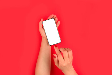 Mockup image of woman's hand holding mobile phone with white blank screen on bright red background - online shopping or online education concept, selective focus