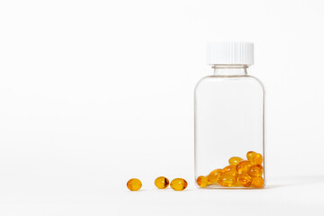 Yellow color fish oil capsules in glass bottle on white background