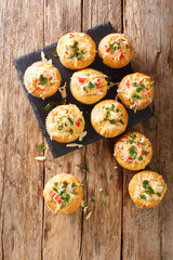 Freshly baked corn muffins with crab meat, herbs and cheese close-up on a slate board on the table. vertical top view from above