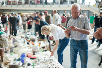 Elderly couple choose things on street market. High quality photo