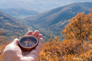 Female hand of traveler, hiker with compass on background autumn forest landscape with mountains on...