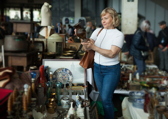Fototapeta na wymiar Elderly woman choose handmade ceramic vase at flea market. High quality photo