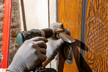 Naklejka premium Close-up, the carpenter installs a custom lock in the front metal door, using a drill and hammer and other tools.