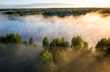 Early morning landscape. Foggy river. River valley in the morning fog at sunrise. View from above. Rays of the sun breaking through the fog in over the trees