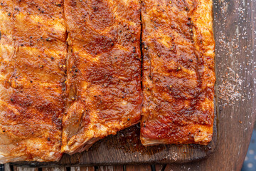 Marinated BBQ pork ribs on a wooden backyard table. Preparation process of barbeque for Grilling, Smoking, Baking and Roasting. Lifestyle concept.