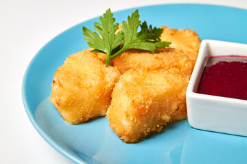 Deep fried cheese nuggets with berry sauce on a blue plate. Close-up, selective focus