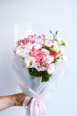 Beautiful woman hands hold bouquet of different flowers white and purple on white background.