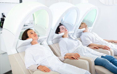 People relaxing in massaging chairs for washing hair in european beauty salon ..