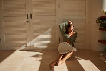 Woman sit on the floor  in the shade on the floor of an apartment, look at th window, hard light