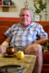 Serious senior man lookingstraight ahead while sitting on a couch in Queensland, Australia