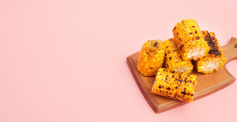 grilled corn on a pastel pink background, copies of space, flatlay