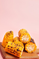 grilled corn on a pastel pink background, copies of space