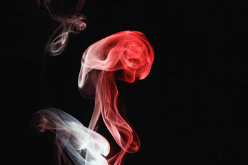 Red smoke on a black background. Colored smoke. Incense stick smoke, illuminated by red light.