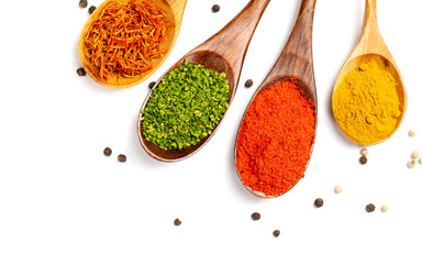 Spices on a white plate in wooden spoons, turmeric, parsley, paprika, saffron, peppercorns.Herbs.Spice in a wooden spoon. Herbs.