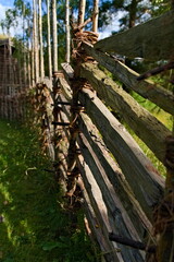 Old wood pole fence from on rural grass meadow. Typical medieval style of fence used in farming.