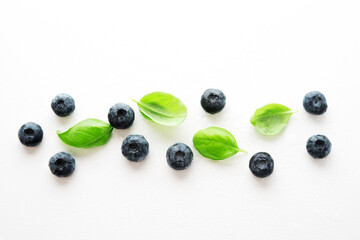 Fresh blueberries and Basil leaves on a white background, top view, flat lay
