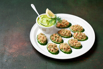 Salmon rillette with avocado on slices of cucumber, selective focus