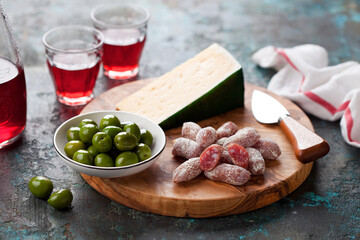 Antipasto Platter. Fuet mini sausages, green olives and cheese on wooden cutting board, selective focus - obrazy, fototapety, plakaty