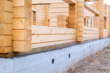 Construction of a wooden house on a cement base, foundation. Suburban real estate, eco house, cottage. Lumber.