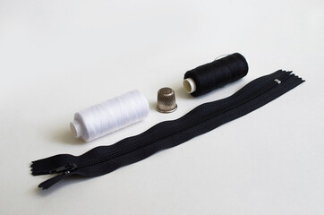 Sewing supplies. Reels with black and white threads, zipper, thimble
