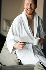 Young handsome man drinking morning coffee in bathrobe