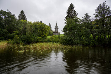 wooden ancient church on the island among the trees during the rain