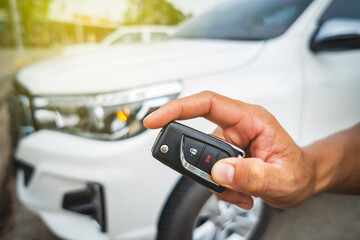 Hand pressing the button on the remote to lock or unlock the car with the remote control.