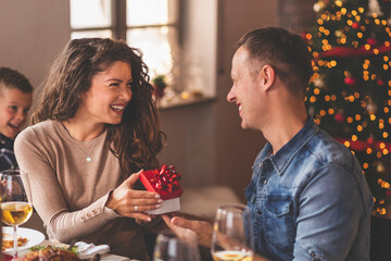 Husband and wife exchanging Christmas presents over dinner