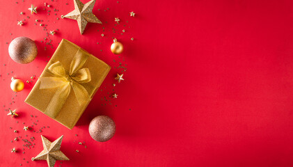 Christmas background decoration concept. Top view of golden gift box with christmas ball and star on red background.